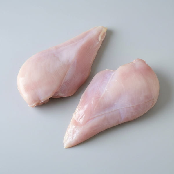Two raw chicken breasts on a wooden cutting board
