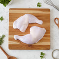 Two raw chicken legs on a wooden surface